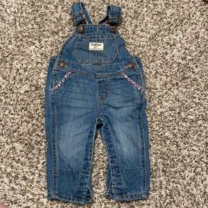 Blue Jean Oshkosh overalls with flor accent on pockets.